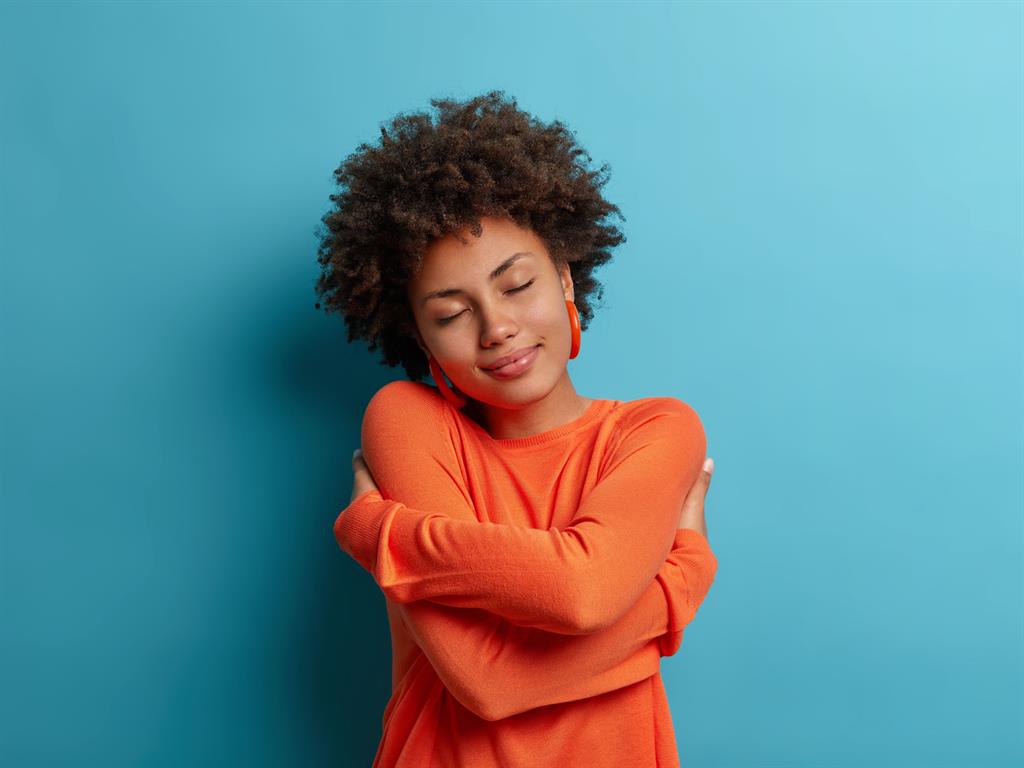 Woman embraces herself, holding her shoulders